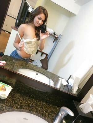 Sassy brunette stripping in front of the mirror and making selfies on ladyda.com