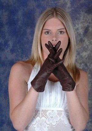 Blonde female pulls on brown leather gloves while wearing a white dress on ladyda.com