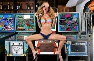 Inked chick Sarah Jessie toys her pussy atop a pinball machine while alone on ladyda.com