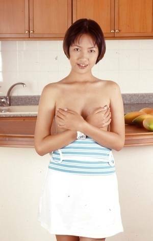 Clothed Asian with tiny tits is posing in the kitchen with spread legs on ladyda.com