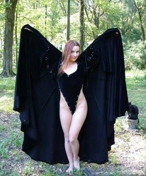 Redhead amateur Amber Lily models nude in a forest draped in a black cape on ladyda.com