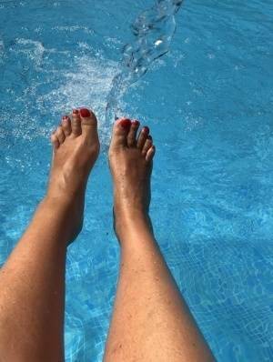Mature woman Sweet Susi dips her painted toenails into a swimming pool on ladyda.com