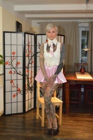Tattooed platinum blonde Miss Francine models a raincoat over a latex dress on ladyda.com