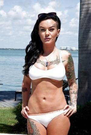 Tattooed whore Lolo Luscious exposing big hooters in swimming pool on ladyda.com