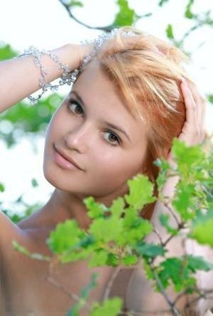 Adorable redhead Violla A displays her naked teen body atop a rock outdoors on ladyda.com