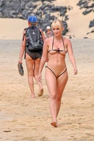 Hot blonde removes a skimpy bikini during a visit to a public beach on ladyda.com